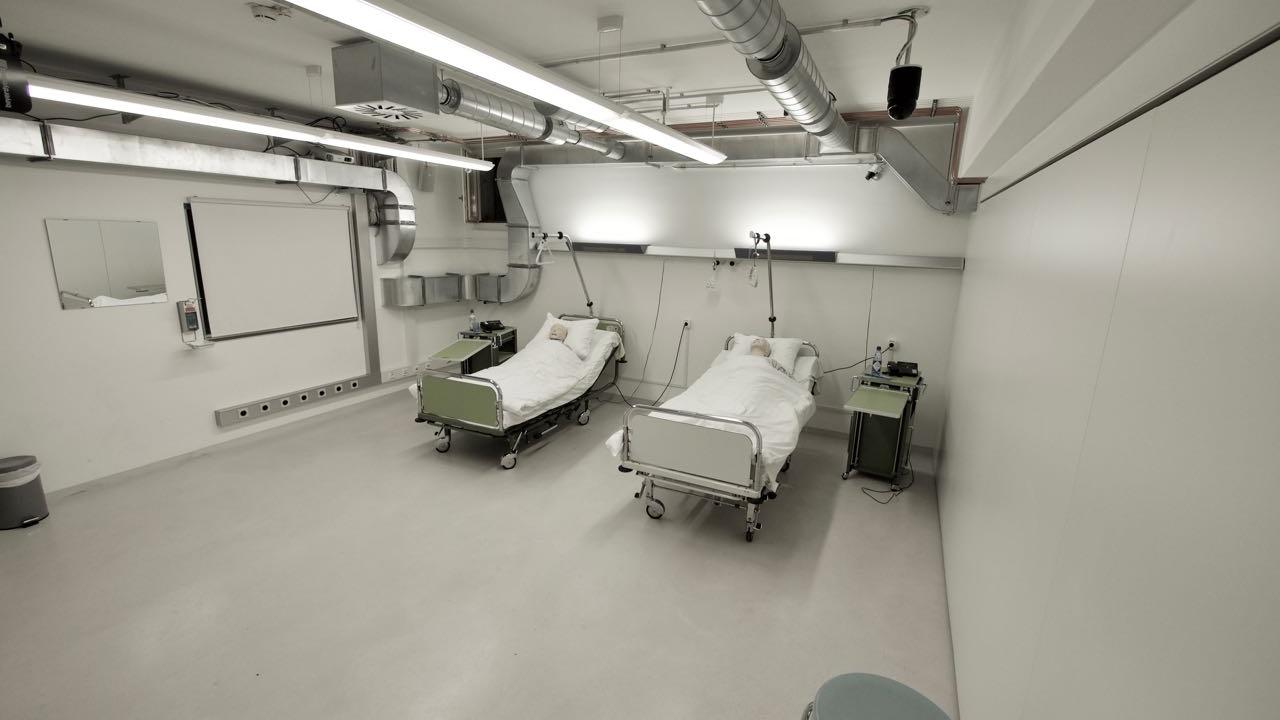 Patientenzimmer: zwei Patientenbetten mit Puppen; zwei Nachtkästchen; sieben Hocker; Trennwand geschlossen
 © 